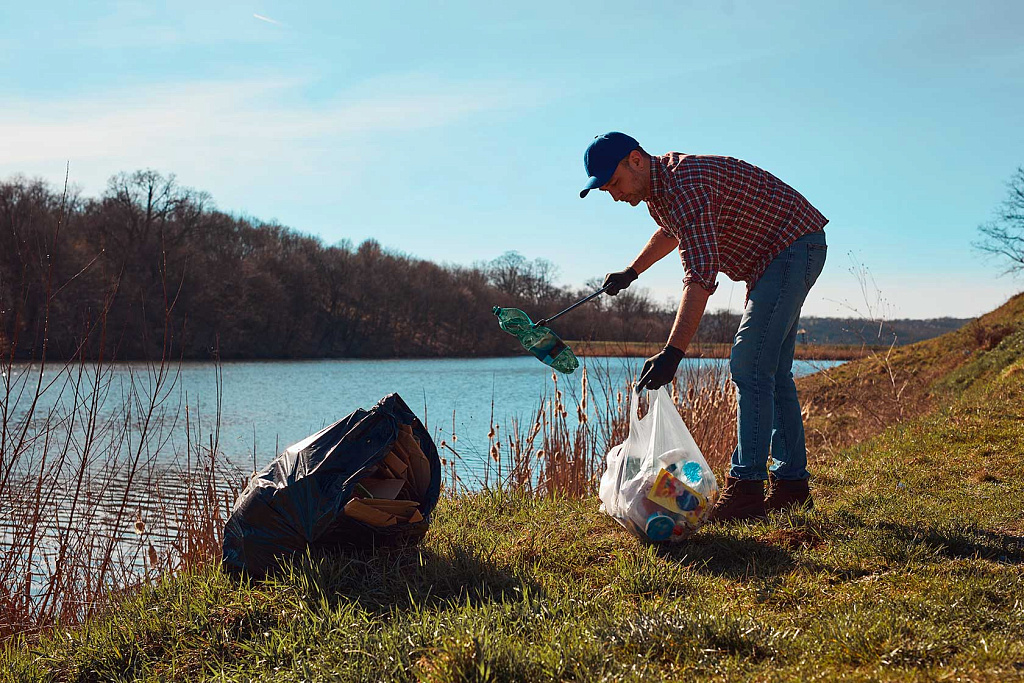  Безопасность экологической среды: волонтёр убирает мусор на берегу